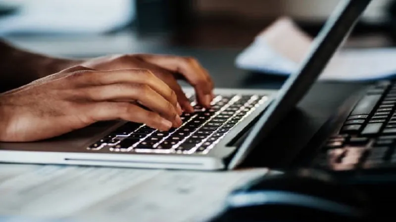 Manos escribiendo en el teclado de un portátil