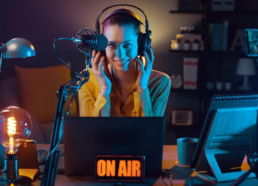 Mujer sonriente con auriculares y micrófono en un estudio con un cartel luminoso de on air