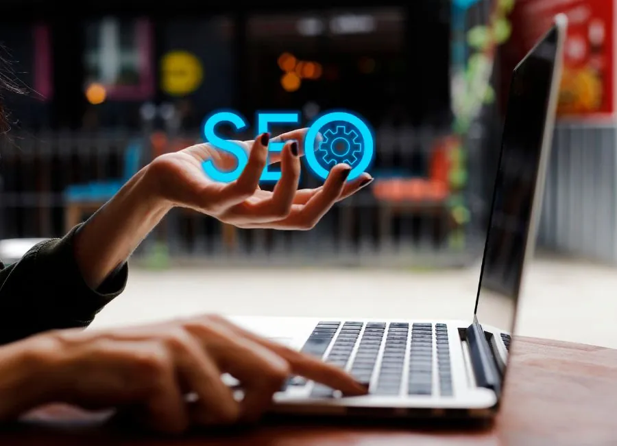 Mano extendida con las letras SEO flotando sobre un portátil